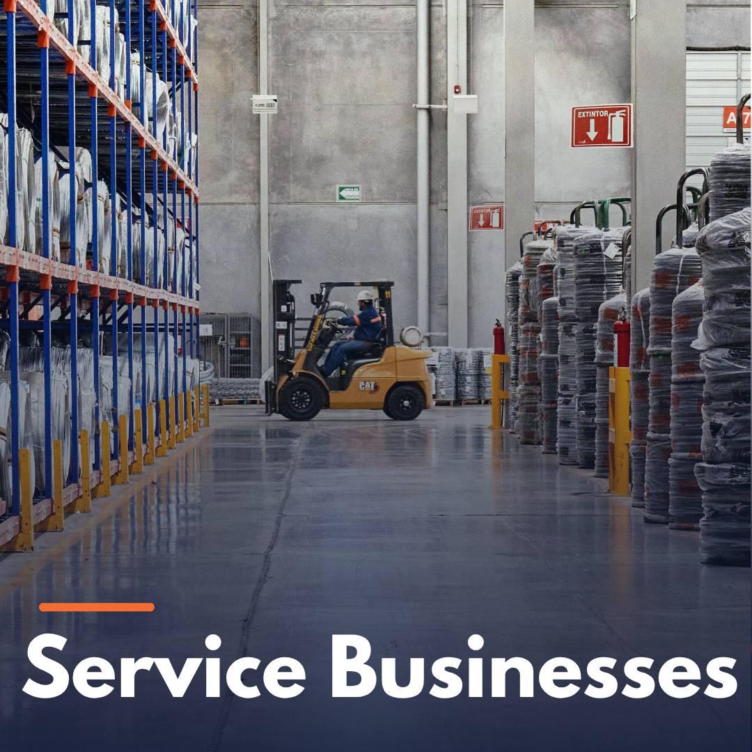 Warehouse interior with stacked goods and forklift operated by a worker wearing a helmet.