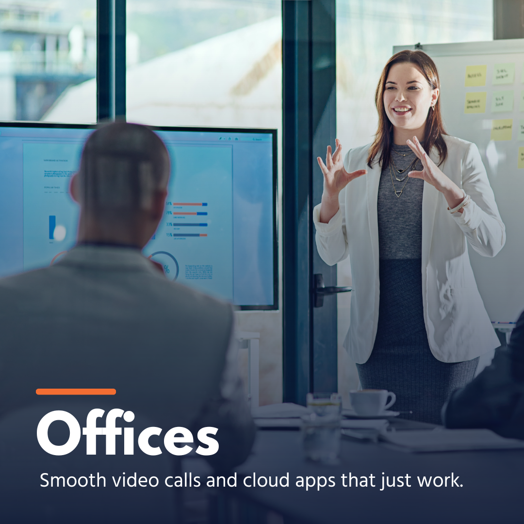 Woman presenting data on screen to people in office during a meeting about video calls and cloud apps.