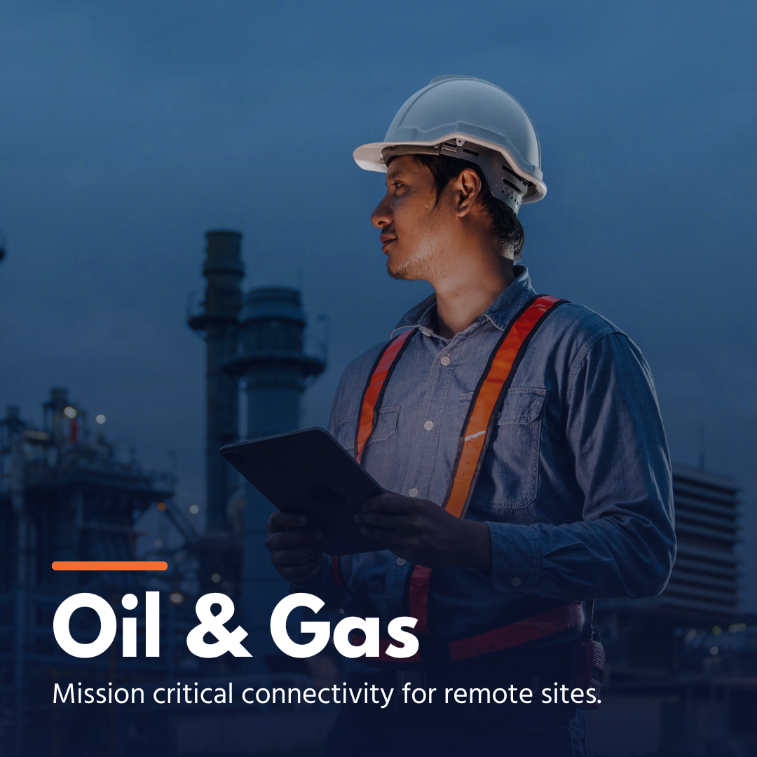 Oil and gas worker in helmet and safety vest holding tablet with industrial facility background.