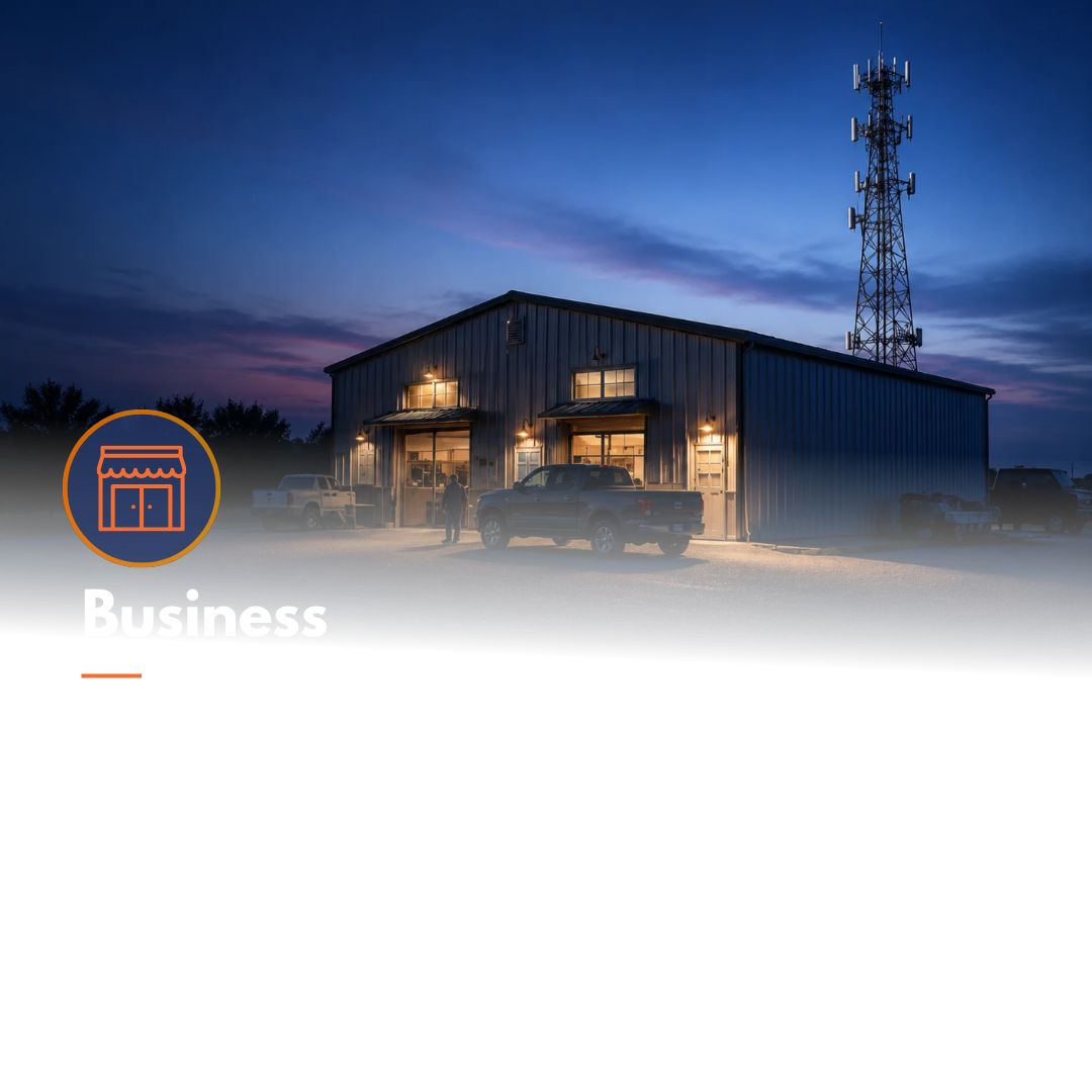 Metal building at dusk with trucks parked outside and a tall communication tower nearby.