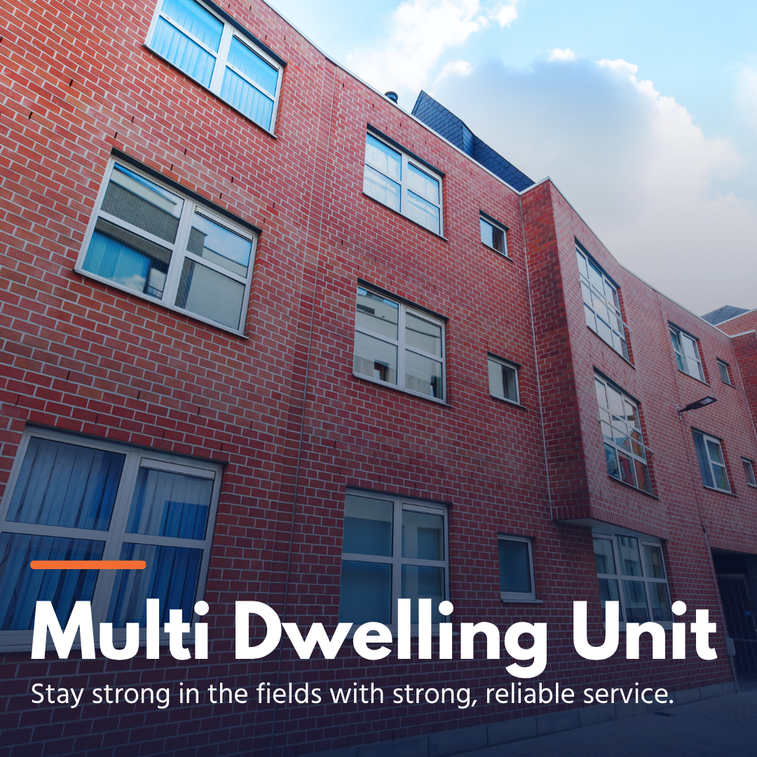 Red brick multi-story residential building with multiple windows under a partly cloudy sky.