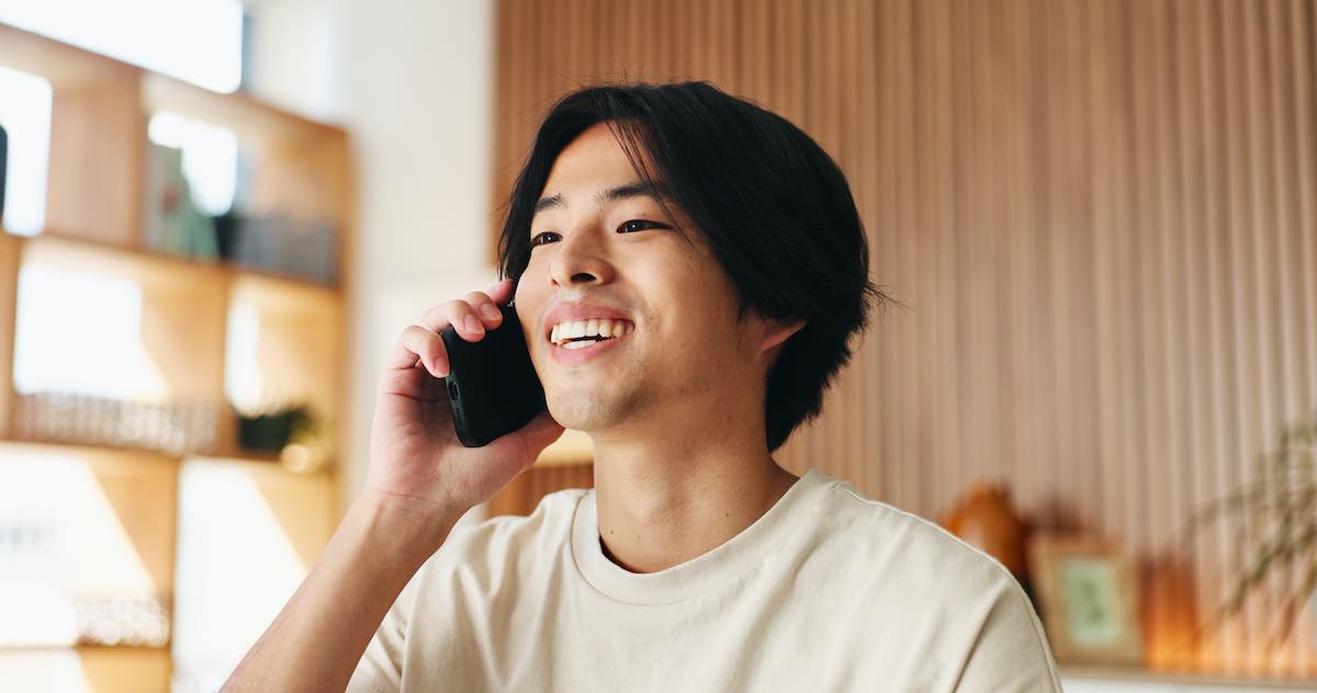 Young man smiling while talking on smartphone in bright, modern interior space