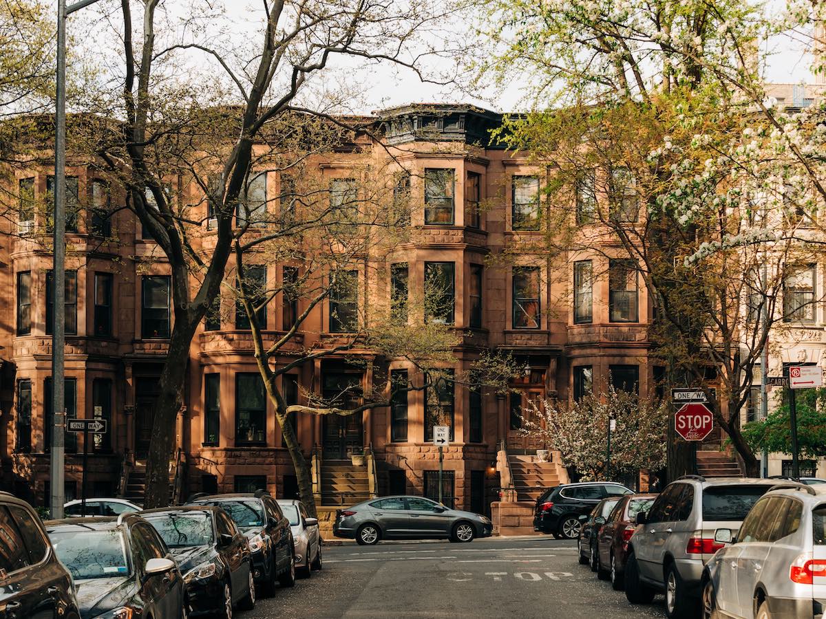 Historic red brick building with bare trees and parked cars on urban street