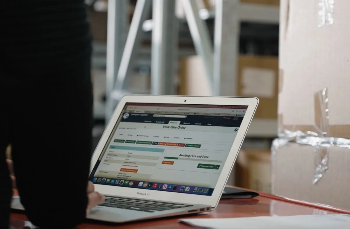 Person using a MacBook Air browsing an order management webpage showing a sale order with status awaiting pick and pack.