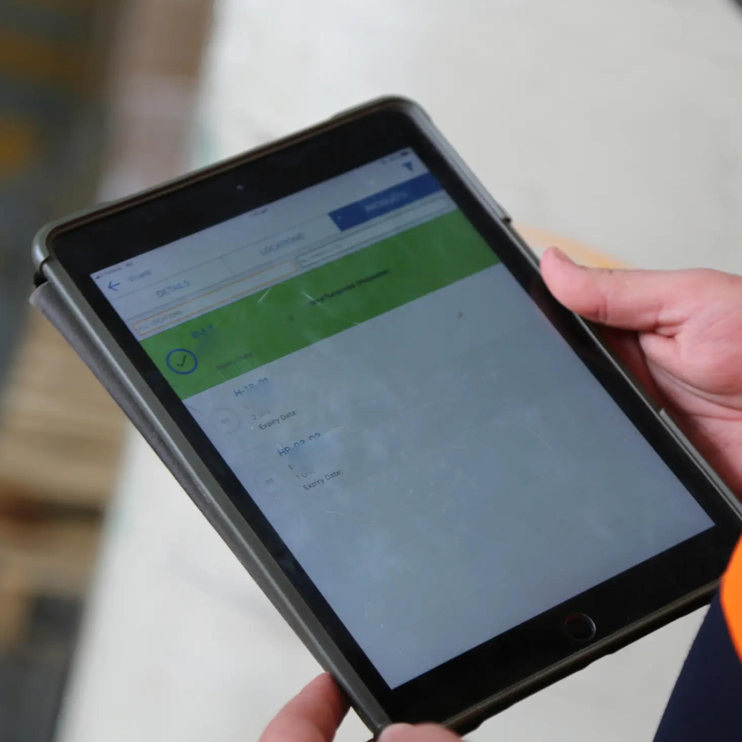 Person holding a tablet showing a software interface with shipment details and status.