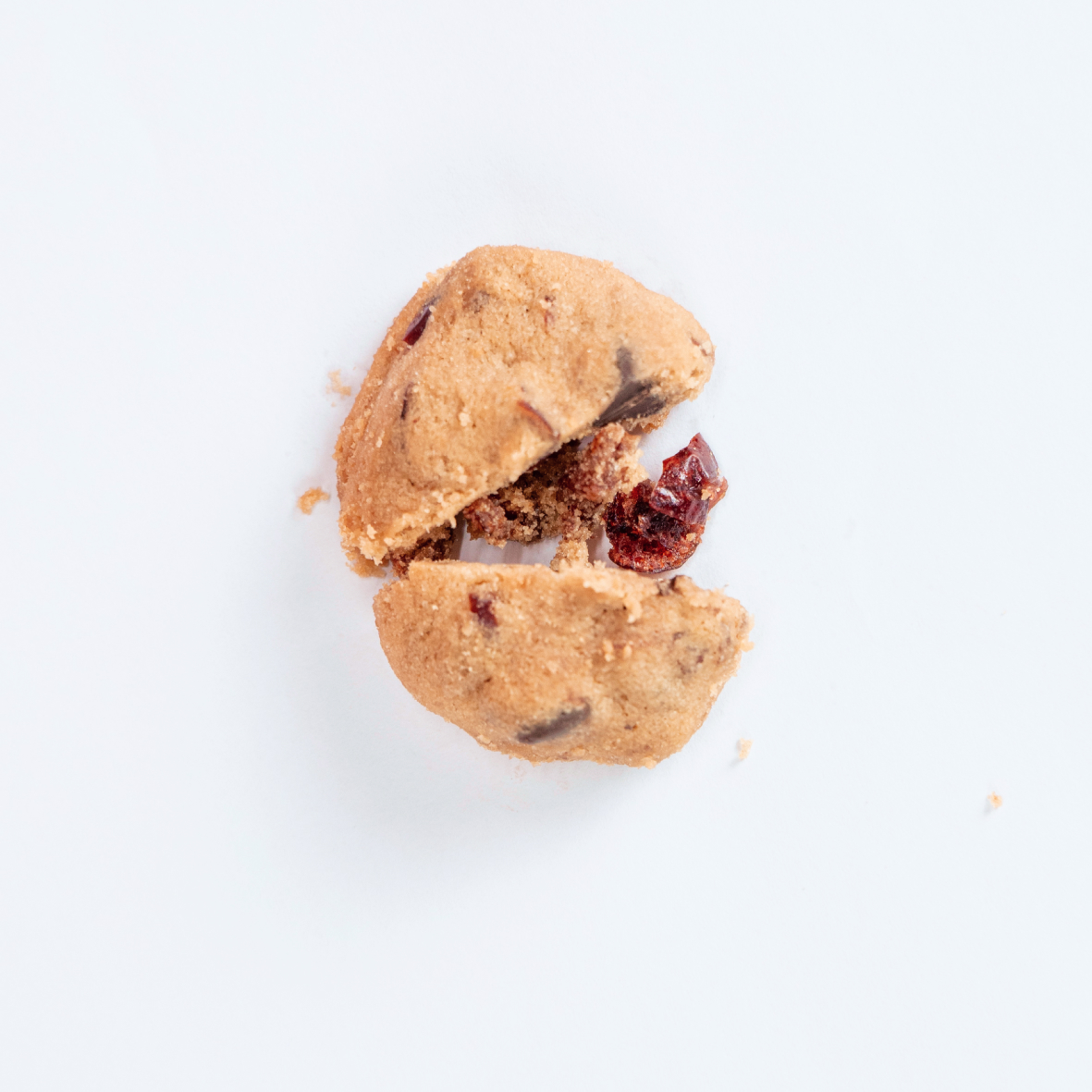 Broken cookie with visible dried cranberry pieces on a white background.
