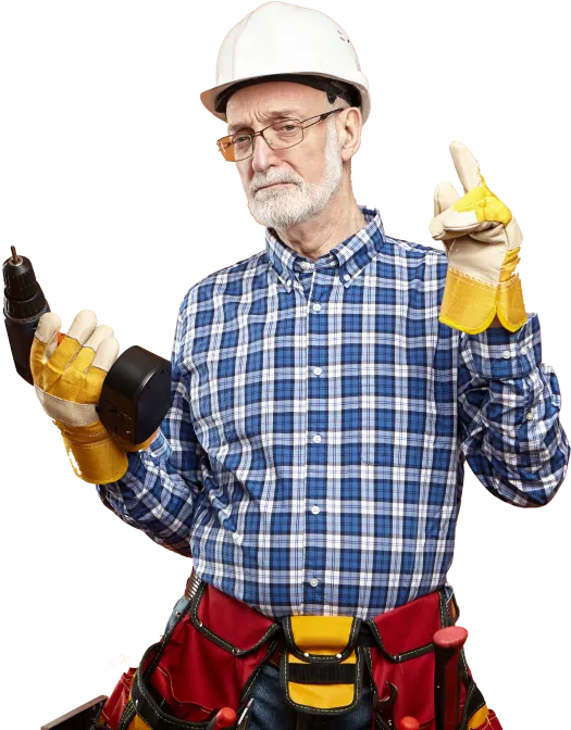 Older man in a white hard hat, glasses, plaid shirt, and yellow work gloves holding a cordless drill and gesturing with his other hand.