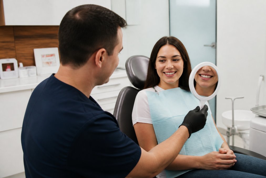 Dentist presenting digital smile simulation on chairside monitor to engaged patient during cosmetic consultation in modern dental office with soft clinical lighting