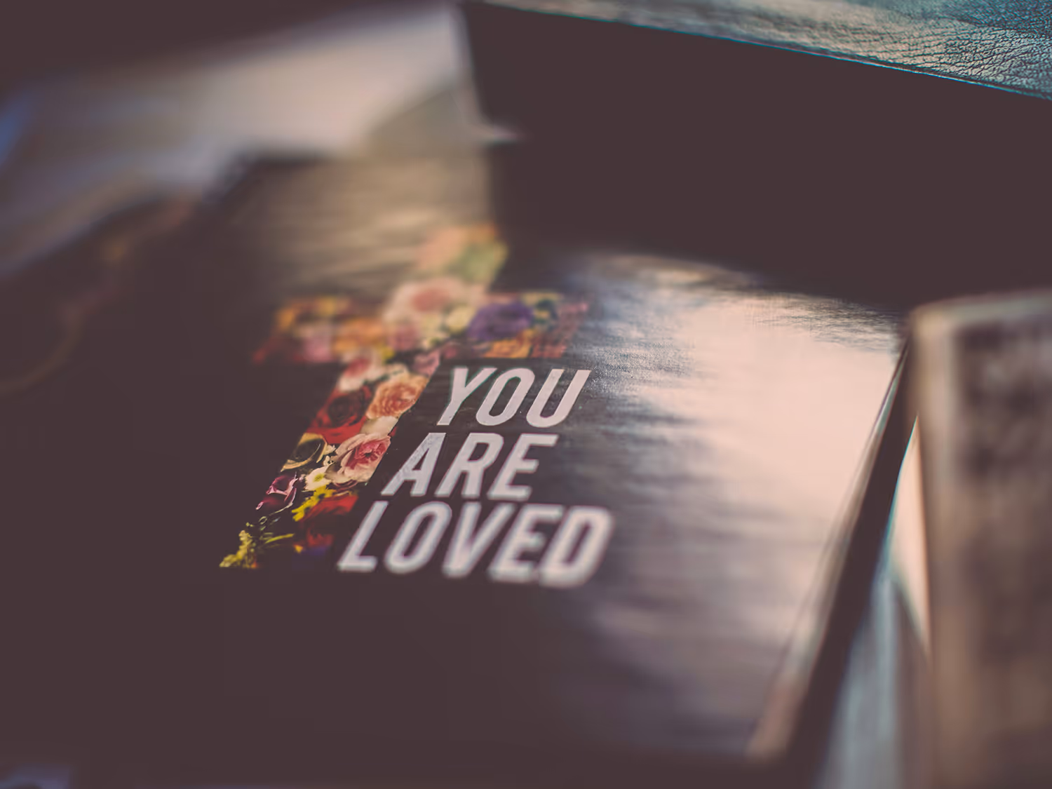 Book with a floral cross on the cover and the words 'You Are Loved' in white lettering.