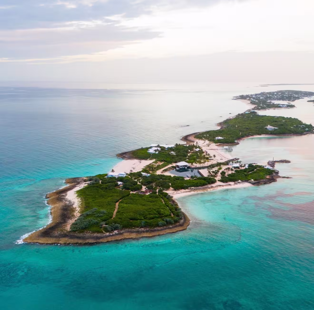 Aerial view of a small island with green vegetation, sandy beaches, and turquoise ocean water.