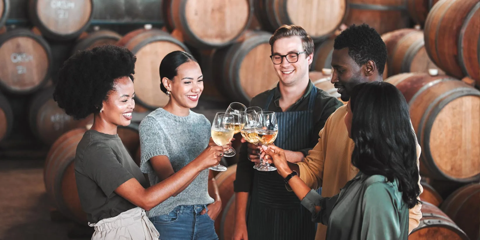 Happy friends cheering with red wine at countryside summer event.