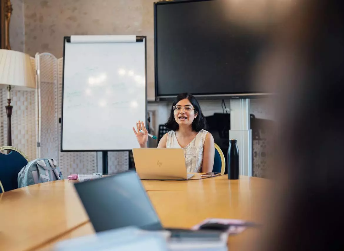A woman with dark hair is conducting an interview via an online video call.