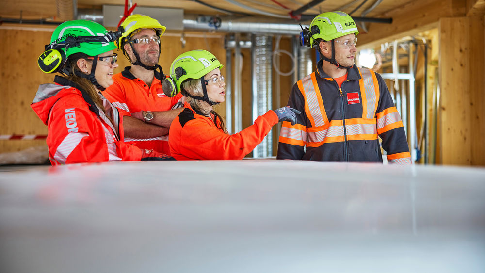 Fire Veidekke-ansatte på byggeplass. Foto.