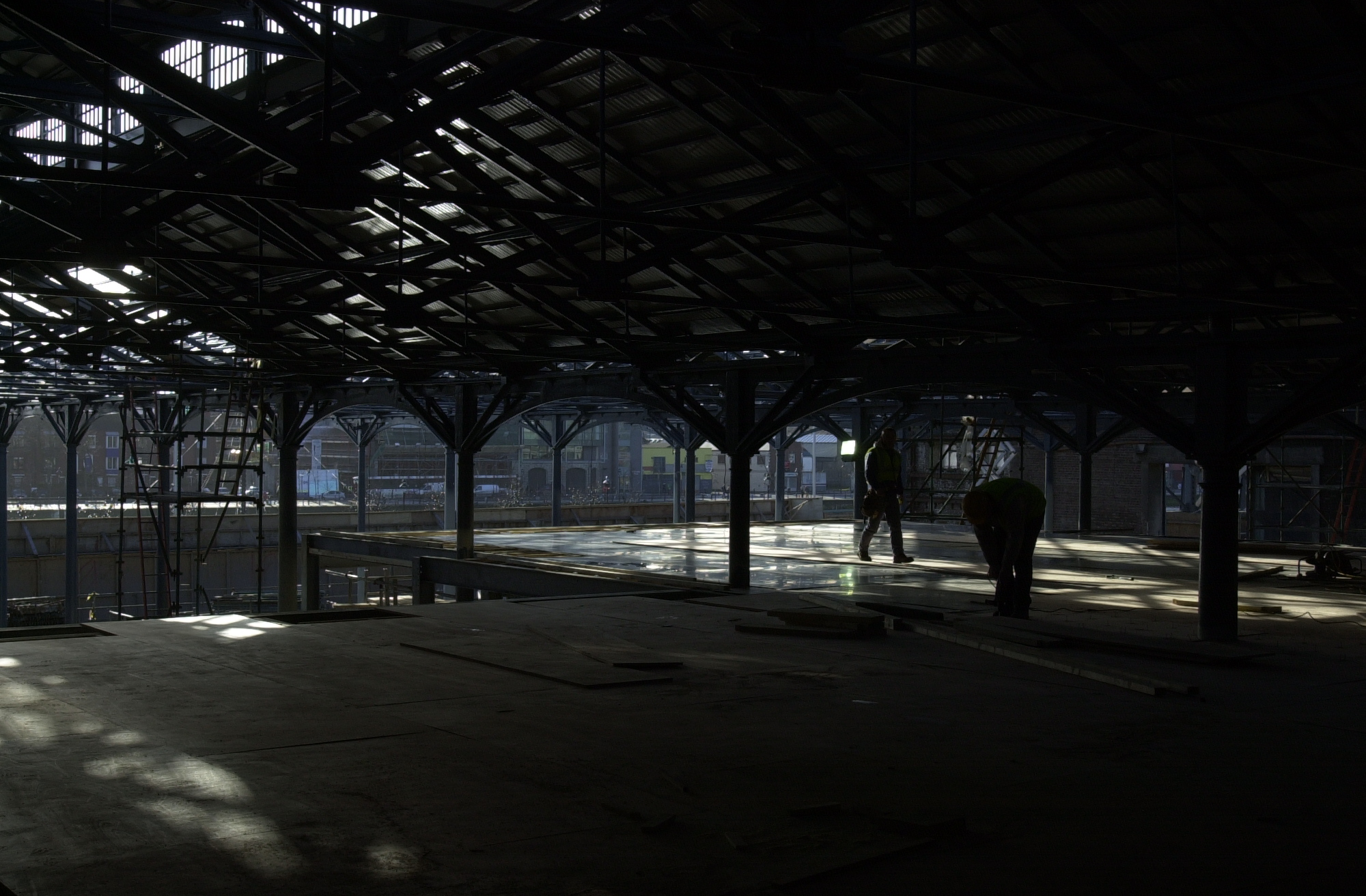 Bright living room with large windows, white sofas, wooden coffee table, and several green indoor plants.