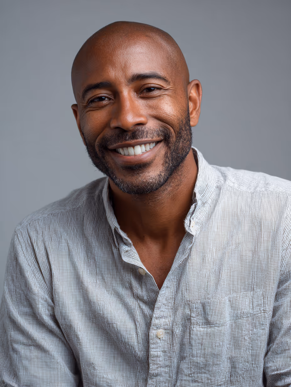 Smiling bald man with a short beard wearing a light gray button-up shirt.