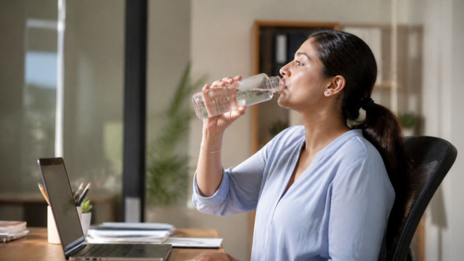 Woman sipping water at her desk
