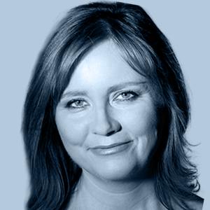 Portrait of a smiling woman with shoulder-length hair against a light blue background.
