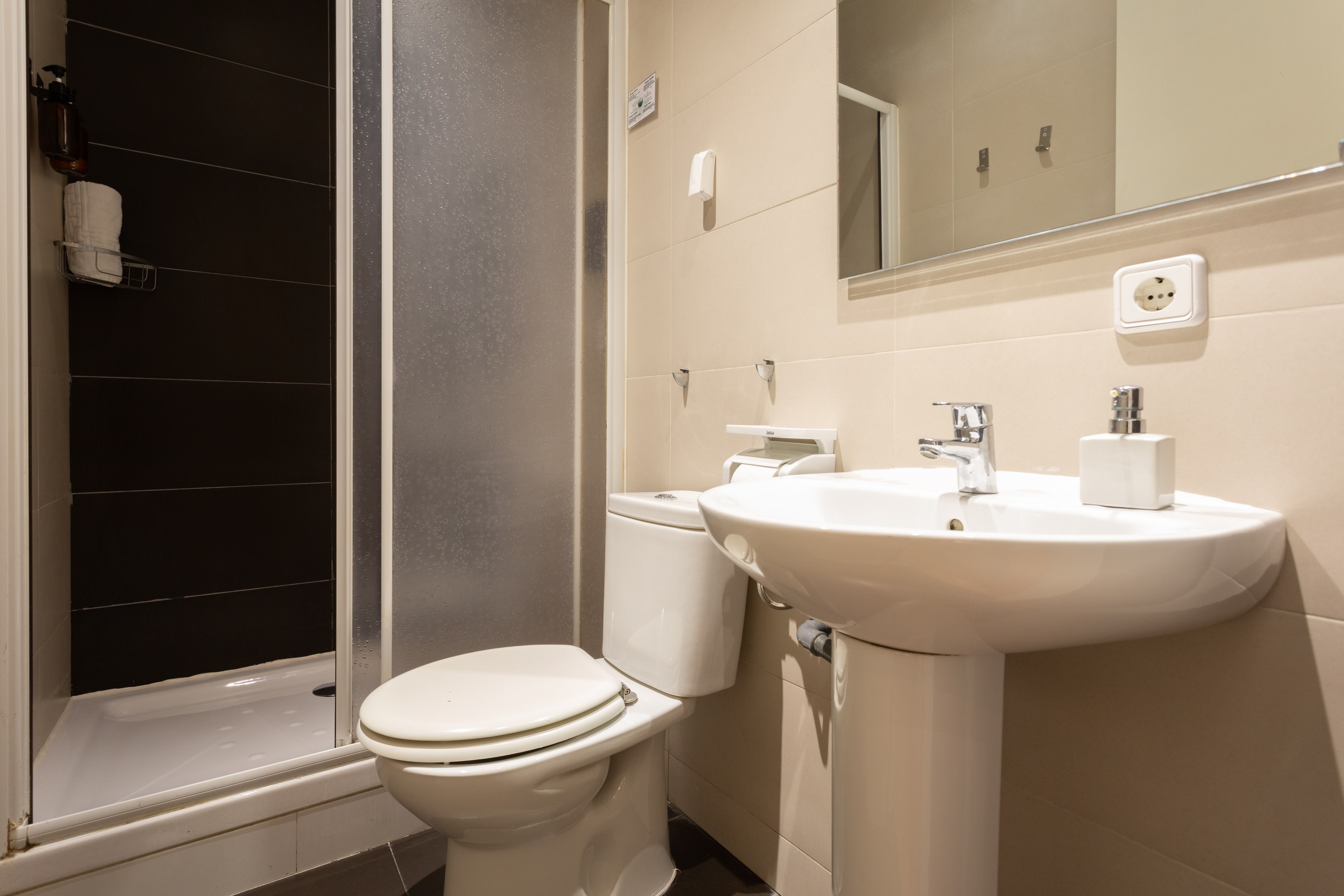 Small bathroom with white toilet, pedestal sink, and a shower with frosted sliding doors.