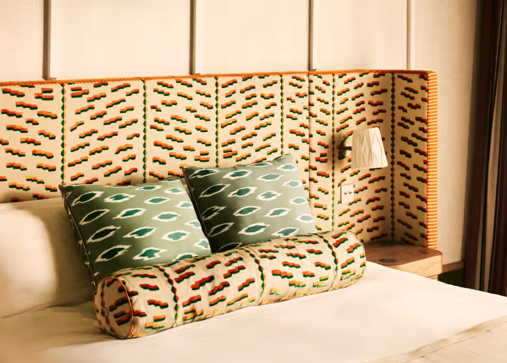 Détails graphiques aux Cimes Bleues : tête de lit brodée et coussins assortis ornent les chambres et suites de votre hôtel au bord de mer et hôtel spa.