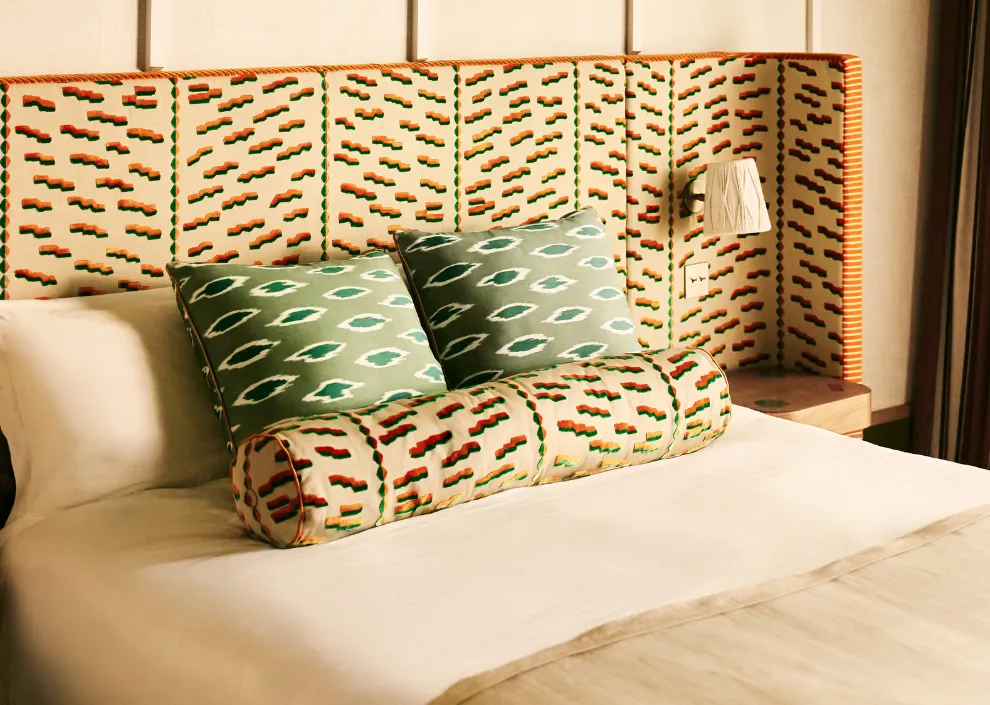 Style éthnique-chic aux Cimes Bleues : tête de lit et traversin à motifs graphiques vert et orange pour vos chambres et suites d'hôtel au bord de mer et hôtel spa.