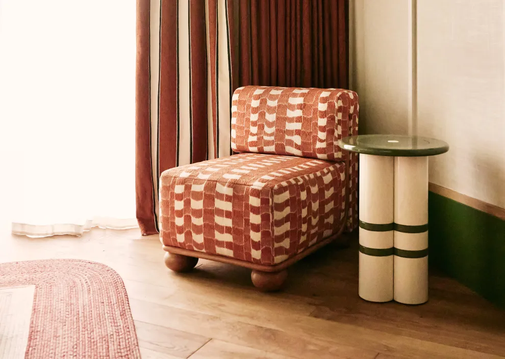 Esprit rétro-chic aux Cimes Bleues : chauffeuse à motifs terre de Sienne et guéridon design dans les chambres et suites de votre hôtel au bord de mer et hôtel spa.