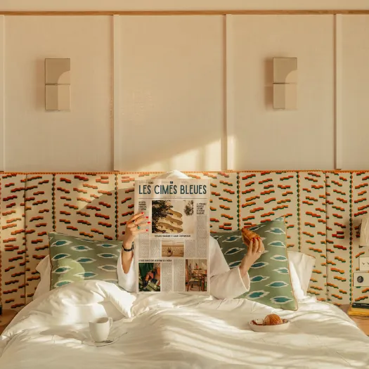 Breakfast in bed with a croissant and the Les Cimes Bleues newspaper in a room with colorful and refined decor, at a 4-star hotel in La Baule.