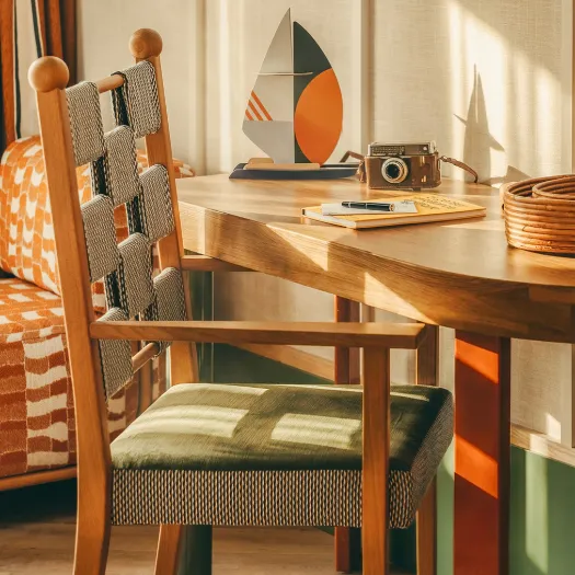 Warm wooden desk with a sailboat model and vintage camera in a sunny room at Les Cimes Bleues, a 4-star hotel in La Baule.