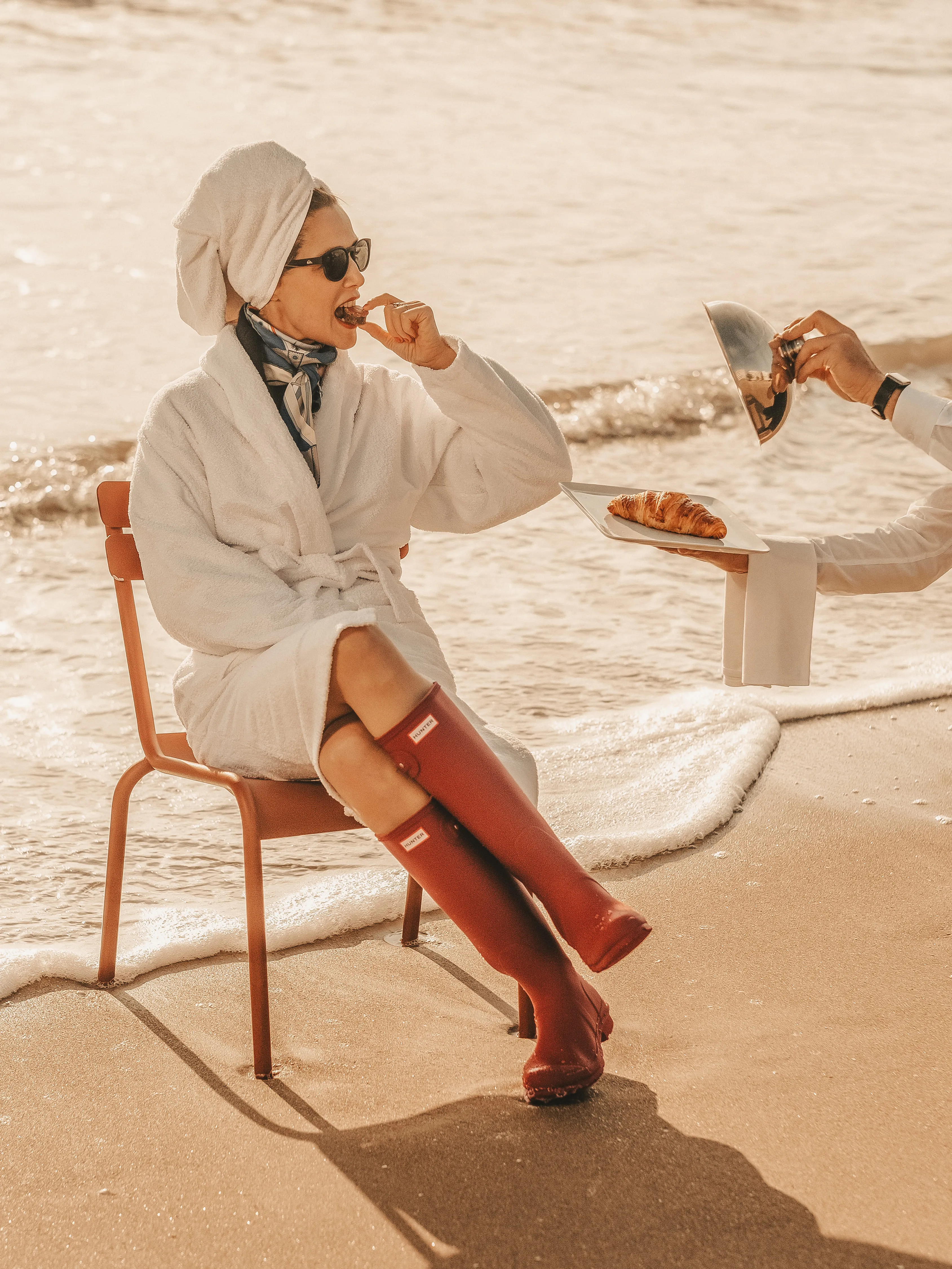 Femme en peignoir dégustant un croissant sur la plage