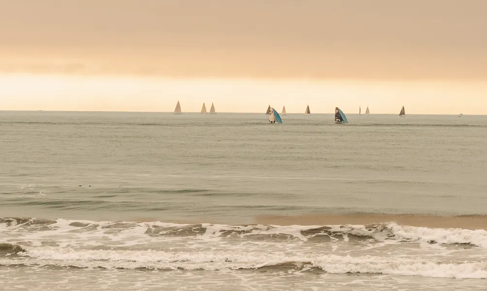 Vue sur la plage bauloise et l'océan Atlantique, avec des voiliers qui naviguent au loin.