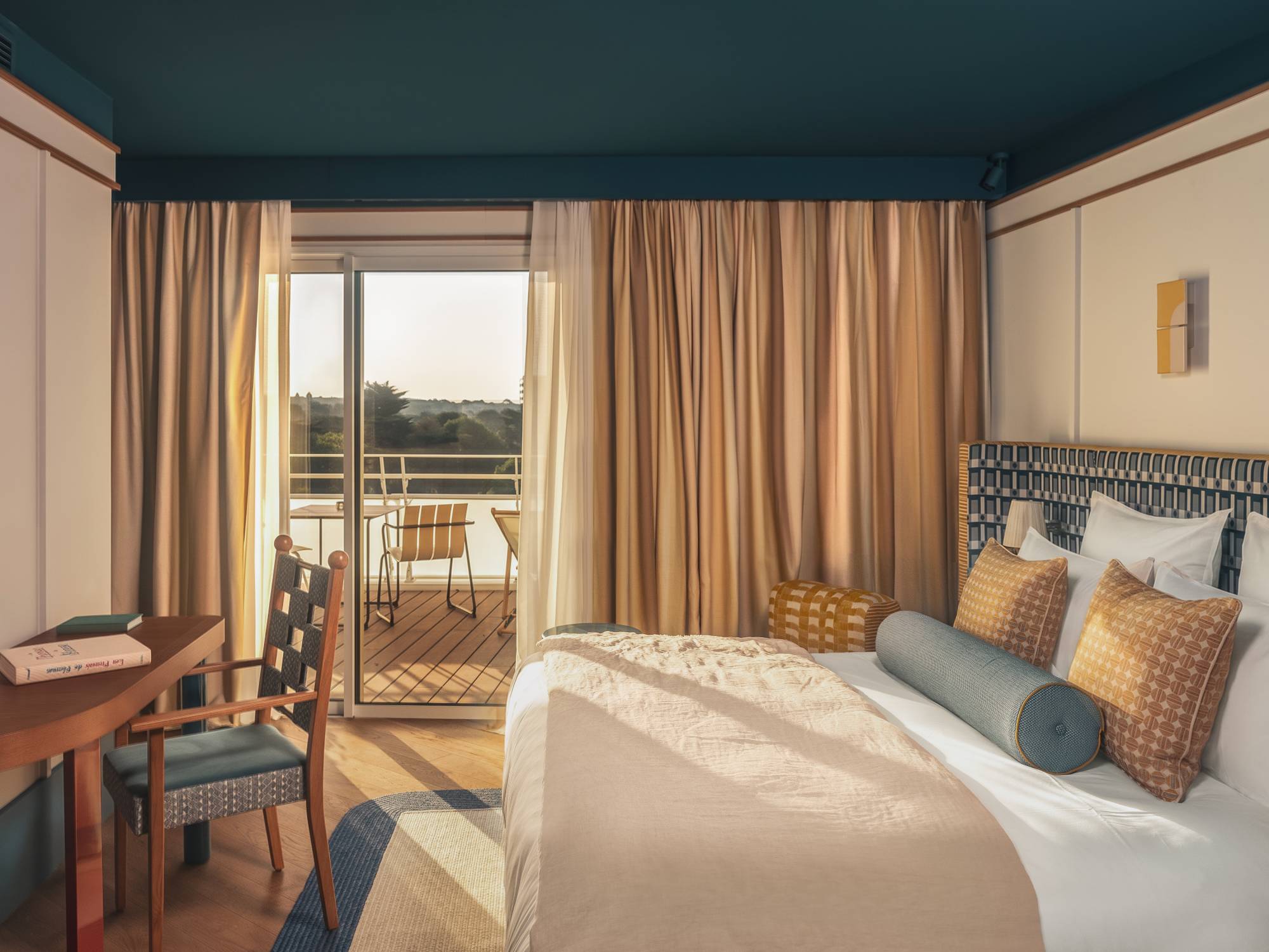 Pause lecture aux Cimes Bleues : détendez-vous dans les chambres et suites design de votre hôtel au bord de mer et hôtel spa, livre orange à la main.