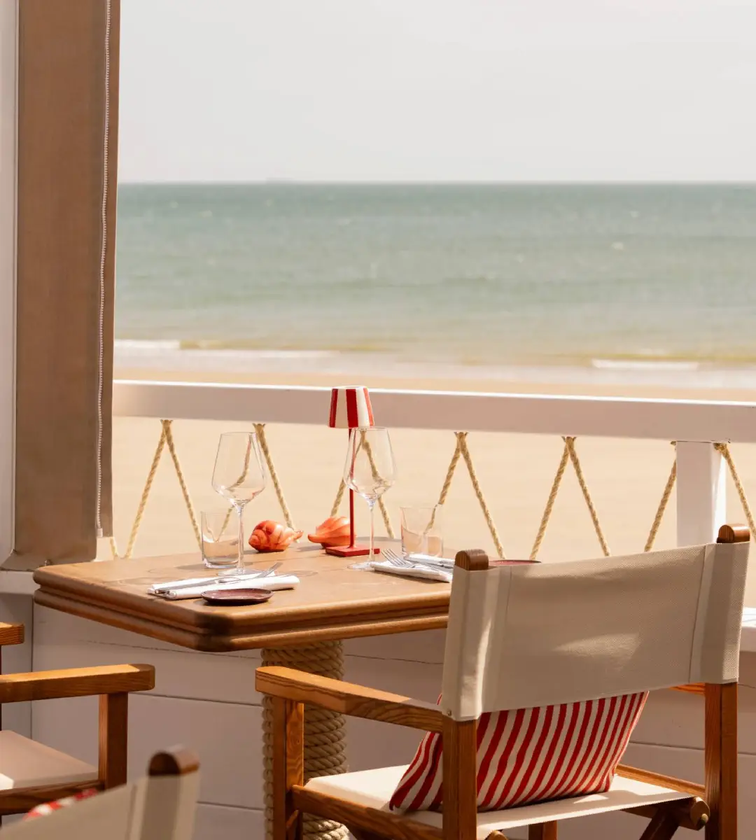 La Cabane Bauloise aux Cimes Bleues : restaurant lumineux aux tables de bois et lampes rouges dans votre hôtel au bord de mer.