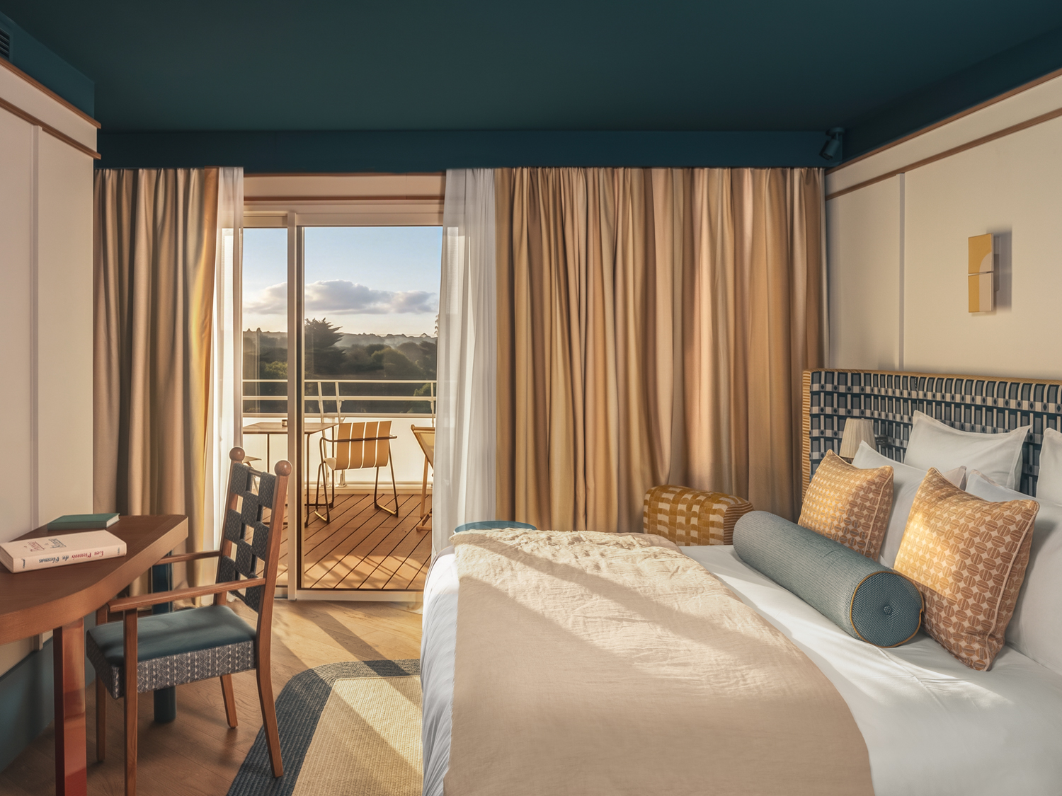 Pause lecture aux Cimes Bleues : détendez-vous dans les chambres et suites design de votre hôtel au bord de mer et hôtel spa, livre orange à la main.