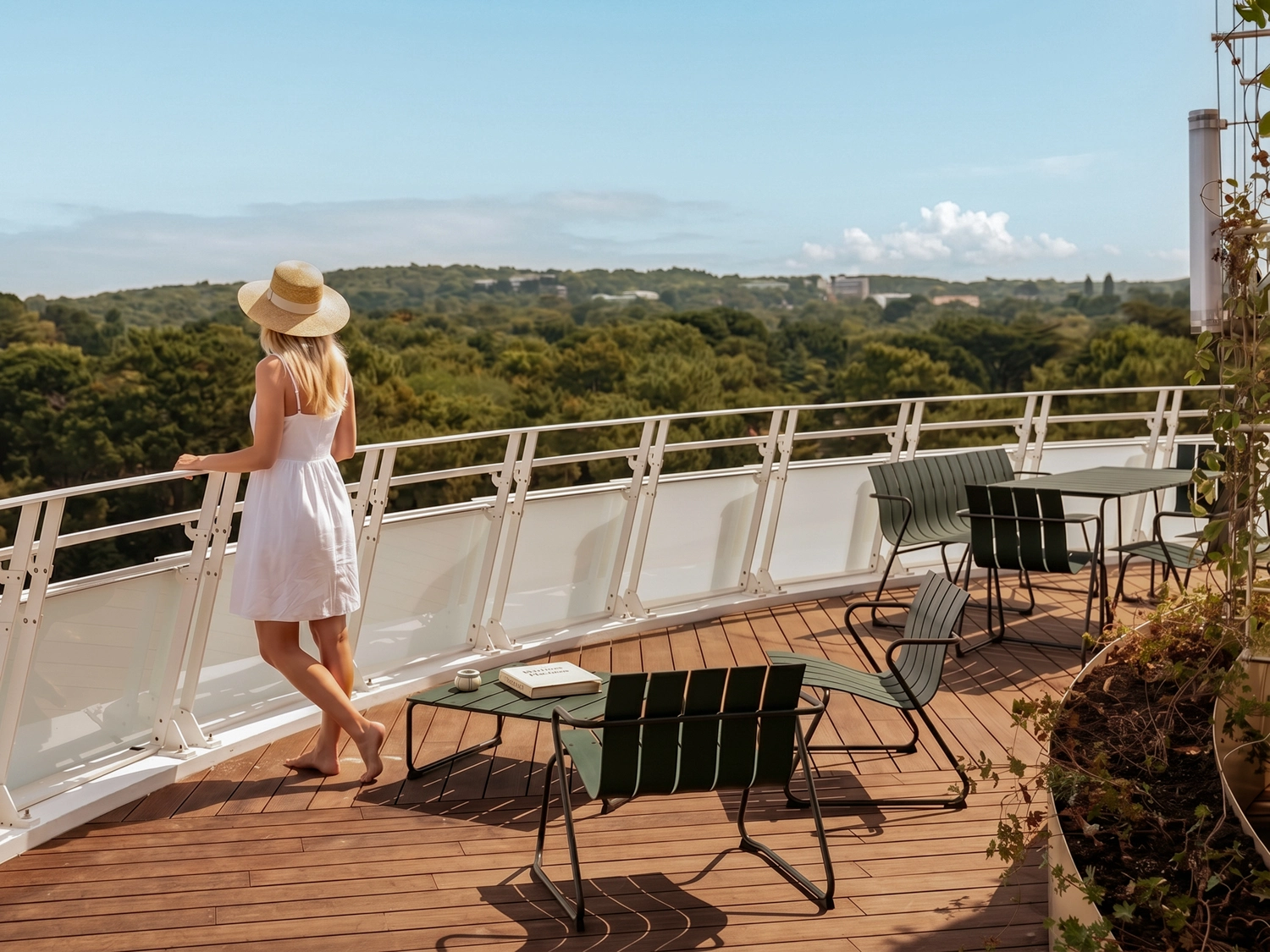 A bottle of Champagne with two glasses set on the table. A woman takes in the view from a large terrace.