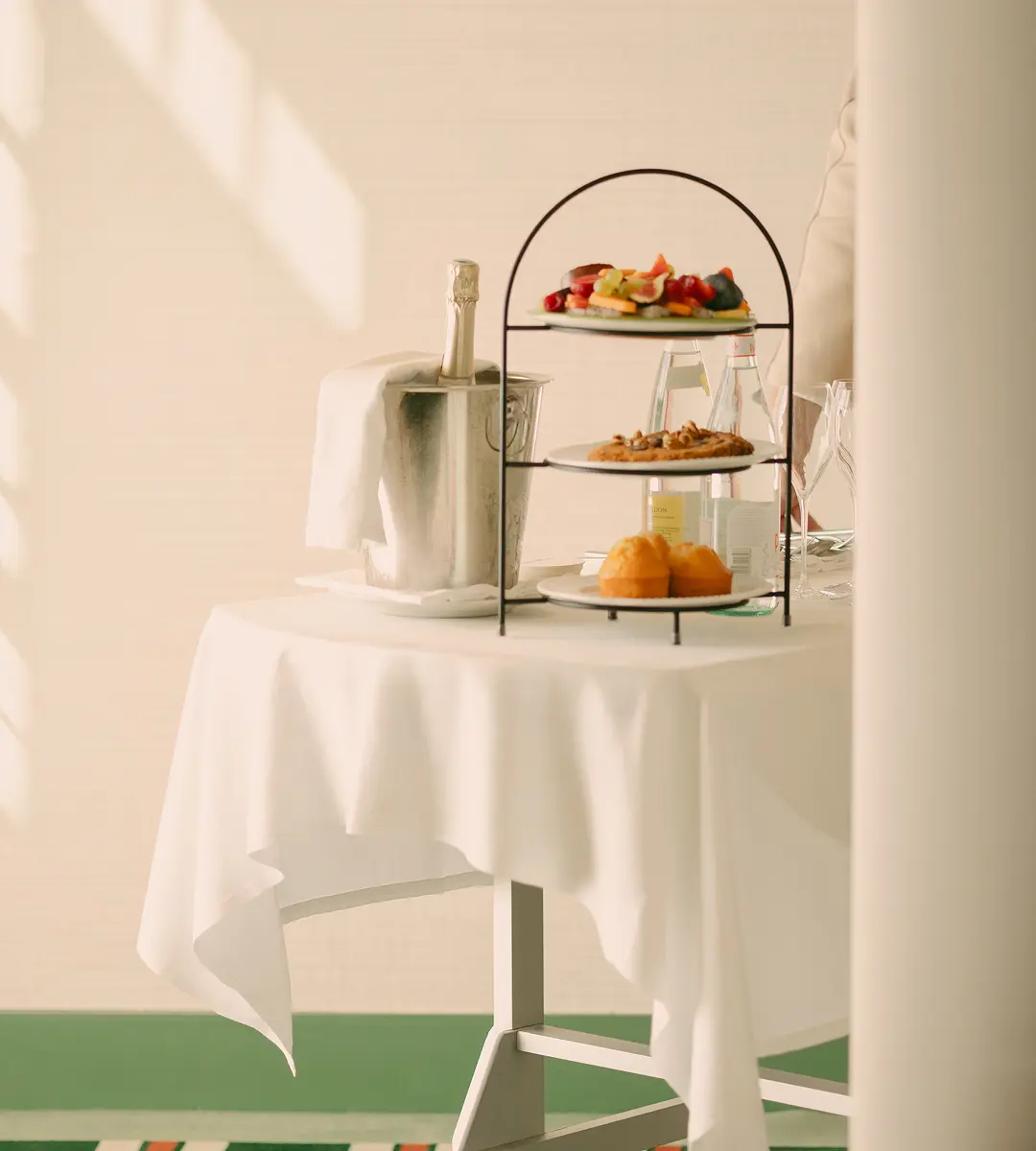 Table dressée pour une expérience gourmande aux Cimes Bleues, avec champagne, pâtisseries et fruits frais présentés sur un serviteur à trois étages.