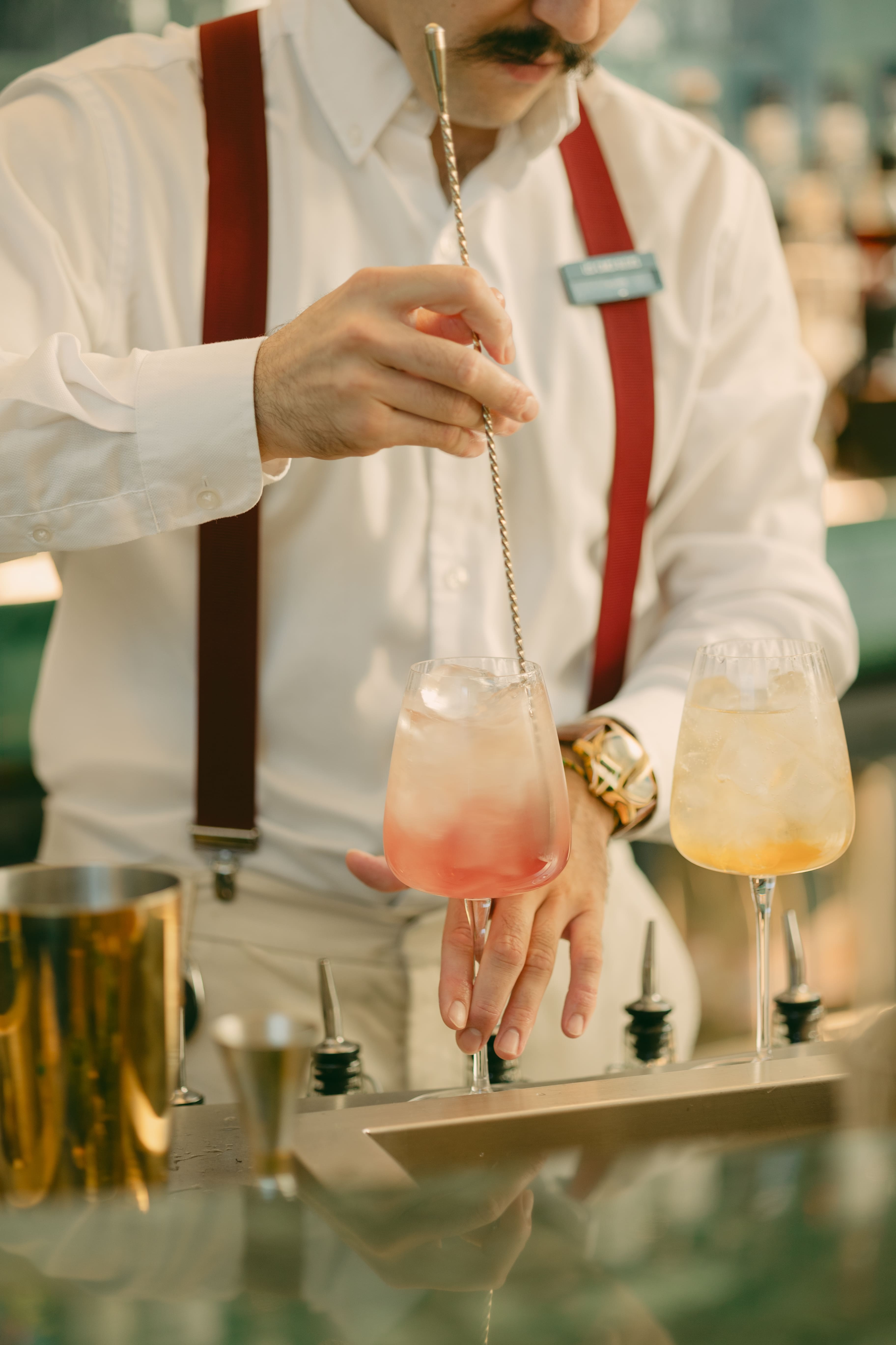 Un barman prépare un cocktail au bar des Cimes Bleues, illustrant l’art de la mixologie et le savoir-faire du bar.