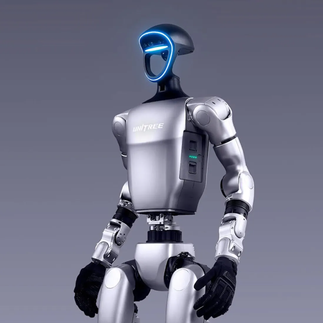 Silver humanoid robot with a glowing blue face outline and black gloves, standing against a gray background.
