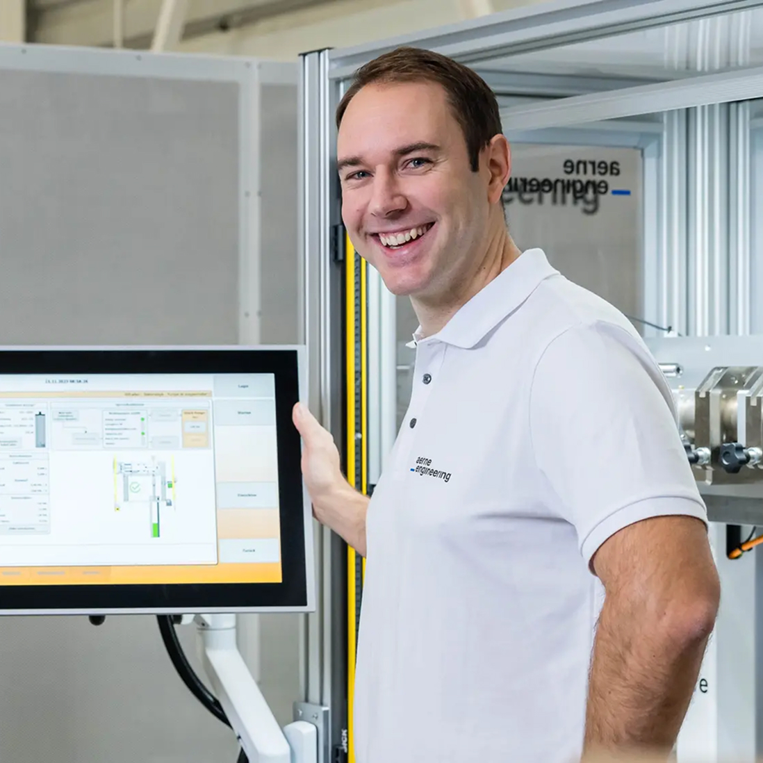 Smiling man in a dark blue shirt sitting at a table with a magazine or document.
