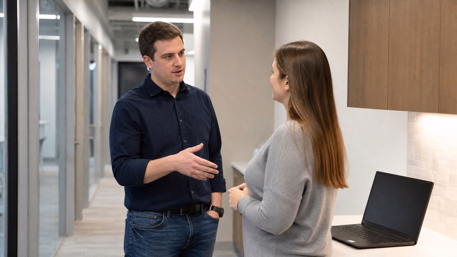 INFORMAL HUDDLE, two people standing and talking near a kitchen counter or