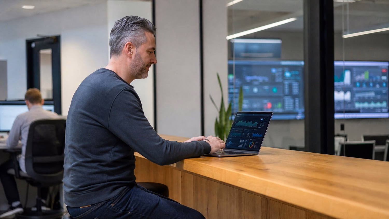 Man at tall desk reviews security alerts on laptop dashboard 75 chars