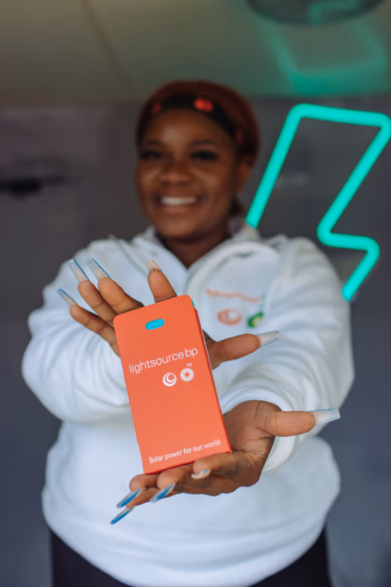 Woman with long nails holding a red Lightsource BP solar power card.
