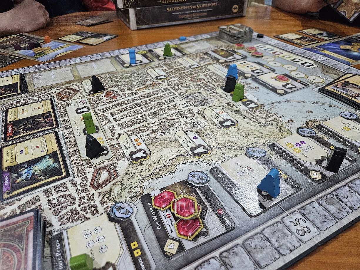 Gameplay photo of the board game Lords of Waterdeep featuring various components and board state.