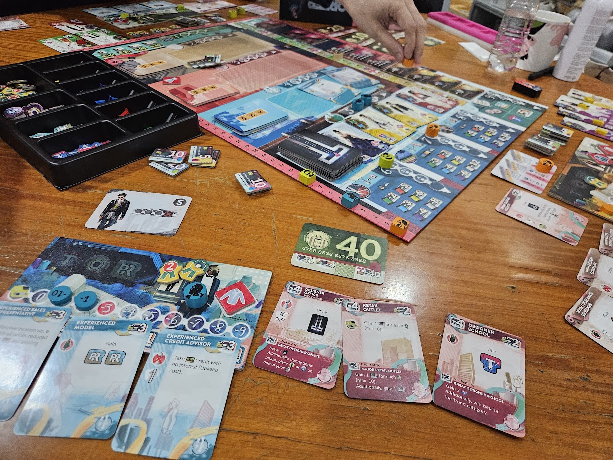Gameplay photo of the board game Prêt-à-Porter featuring various components and board state.