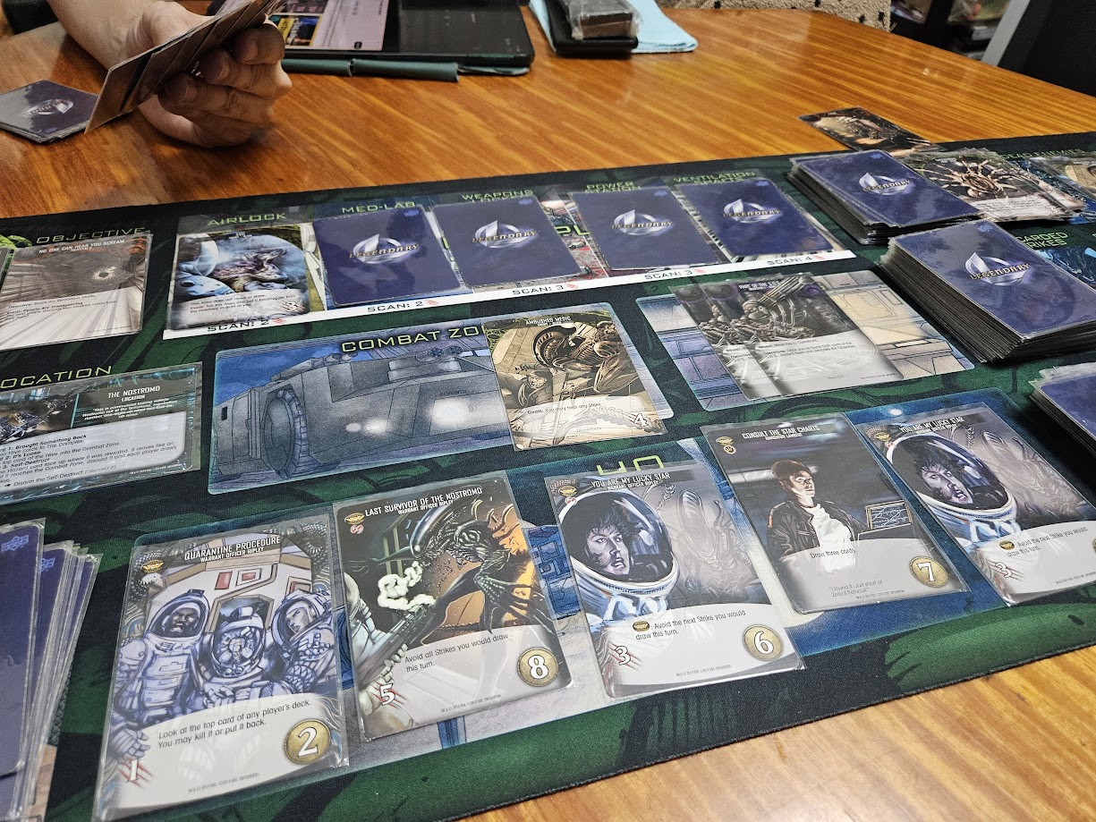 Gameplay photo of the board game Legendary Encounters: An Alien Deck Building Game featuring various components and board state.