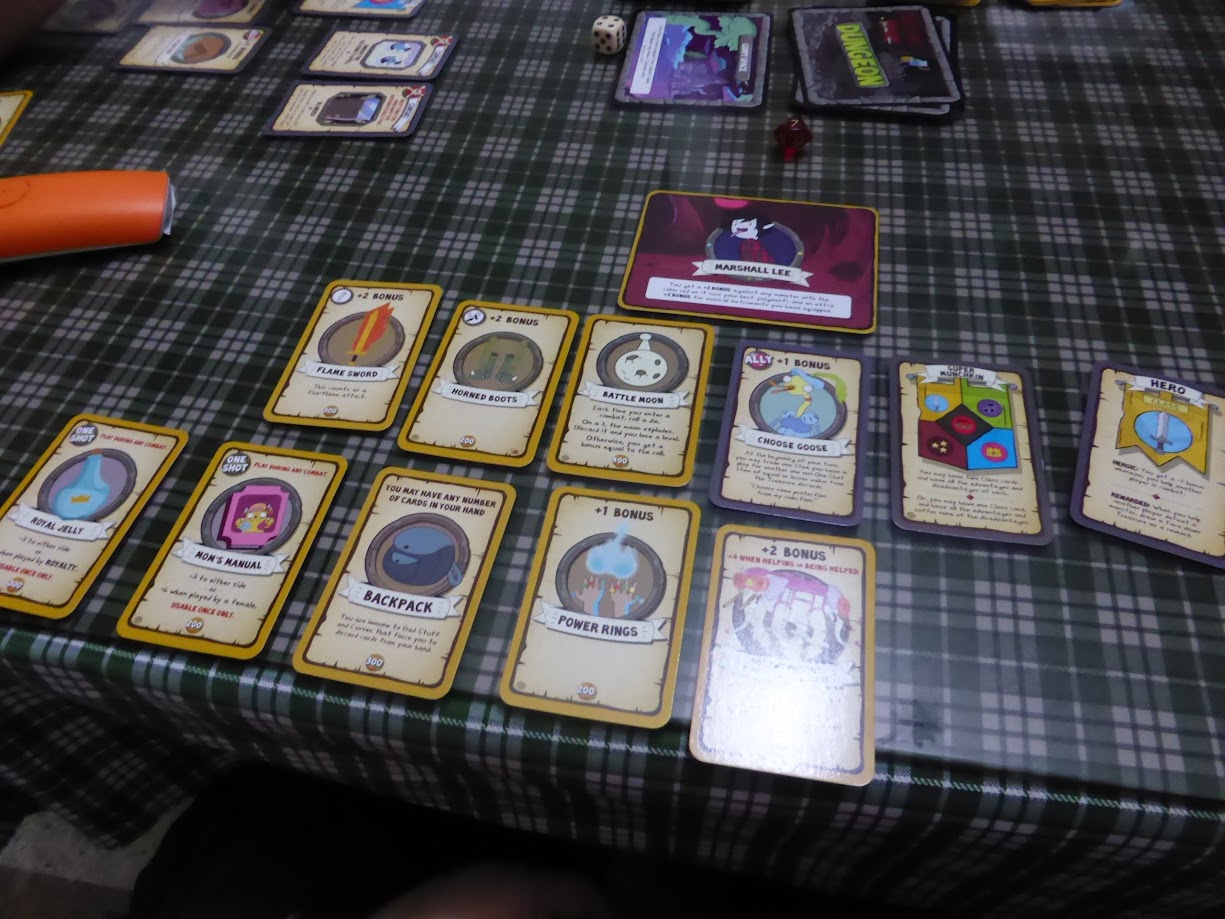 Gameplay photo of the board game Munchkin Adventure Time 2: It's a Dungeon Crawl! featuring various components and board state.