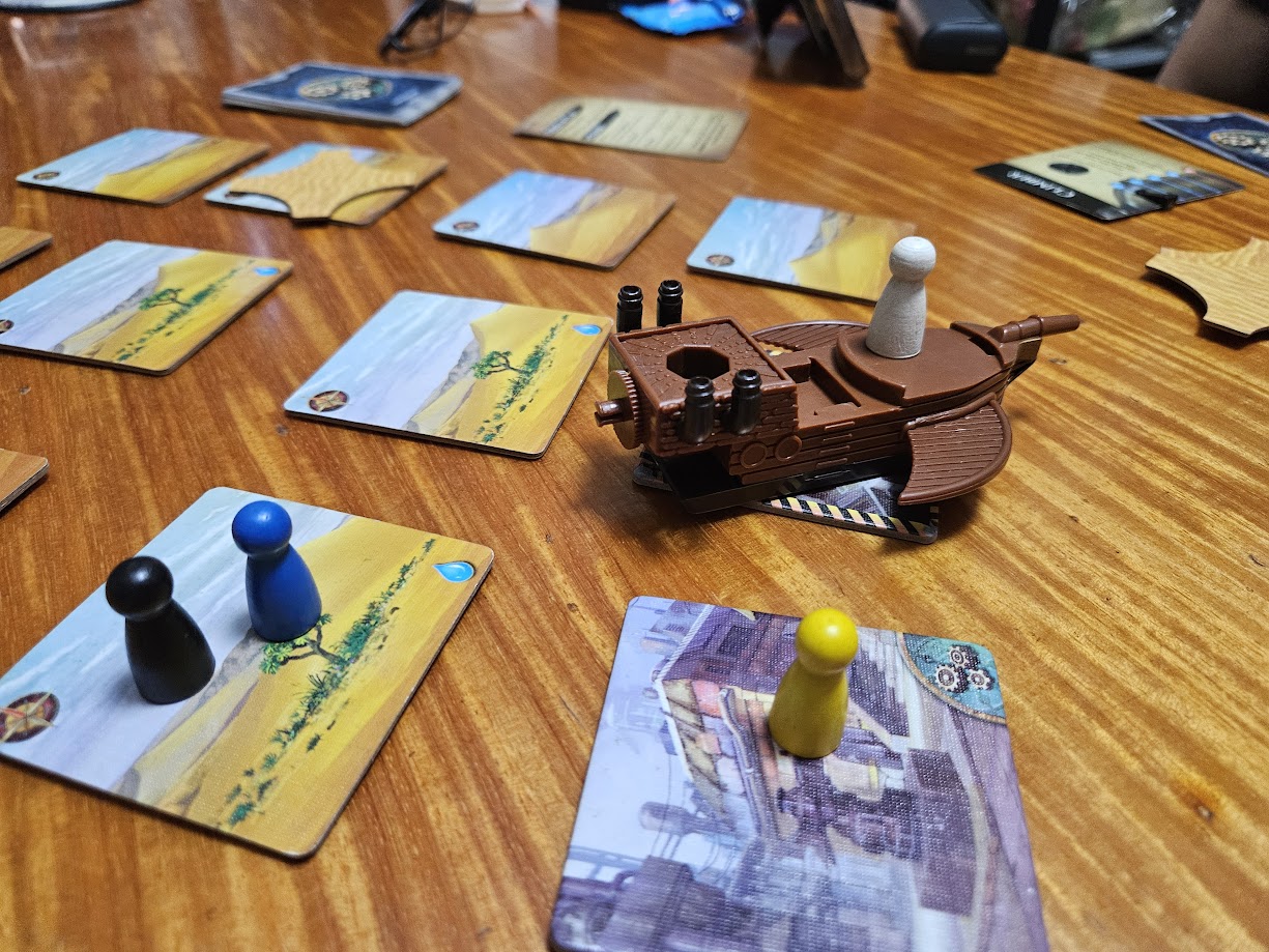 Gameplay photo of the board game Forbidden Desert featuring various components and board state.
