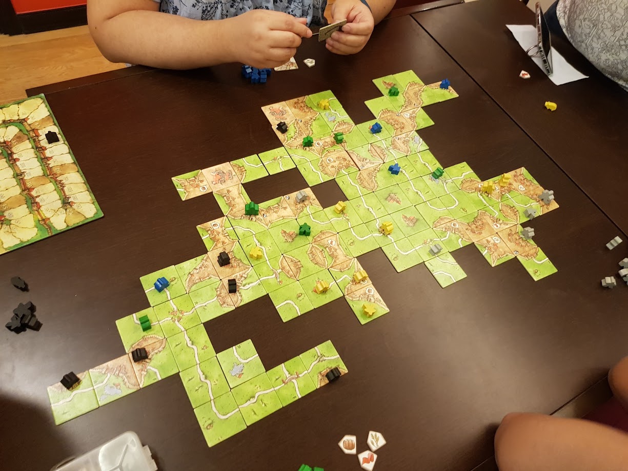 Gameplay photo of the board game Carcassonne: The Expansion featuring various components and board state.