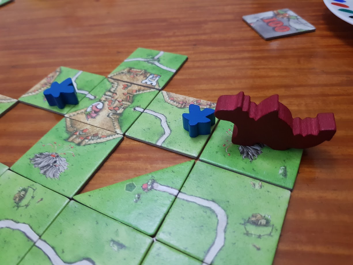 Gameplay photo of the board game Carcassonne: The Princess & the Dragon featuring various components and board state.