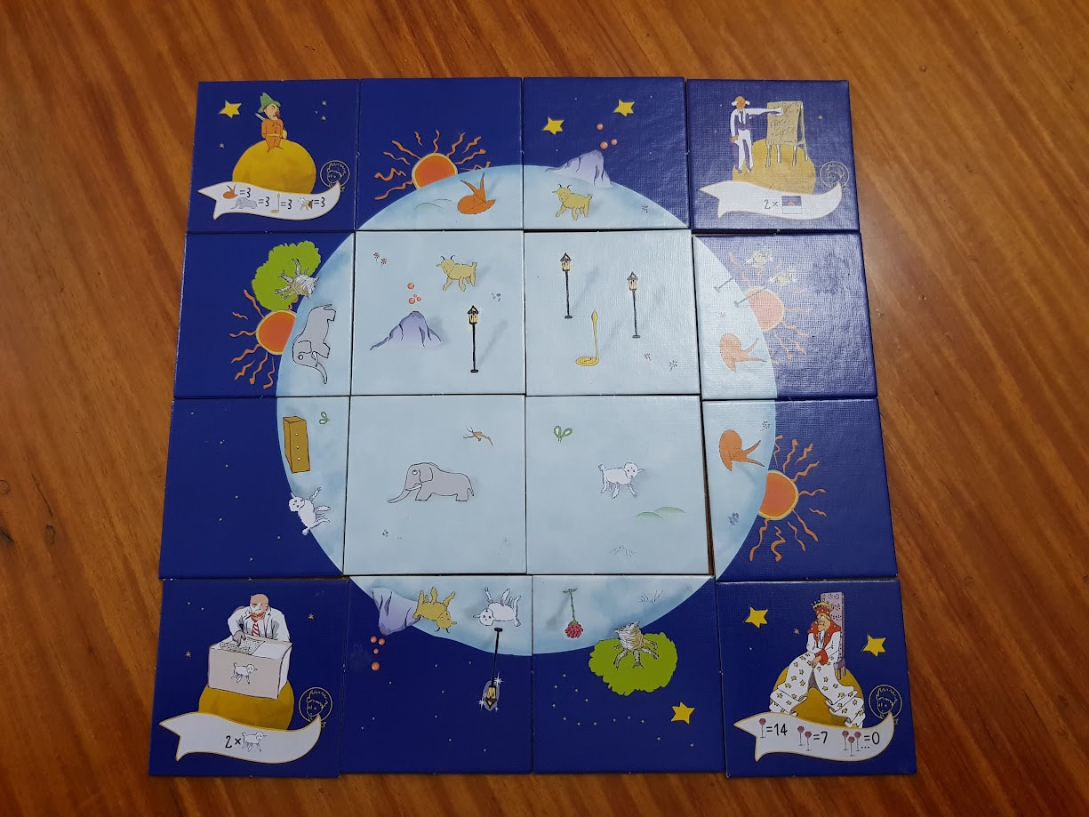 Gameplay photo of the board game The Little Prince: Make Me a Planet featuring various components and board state.