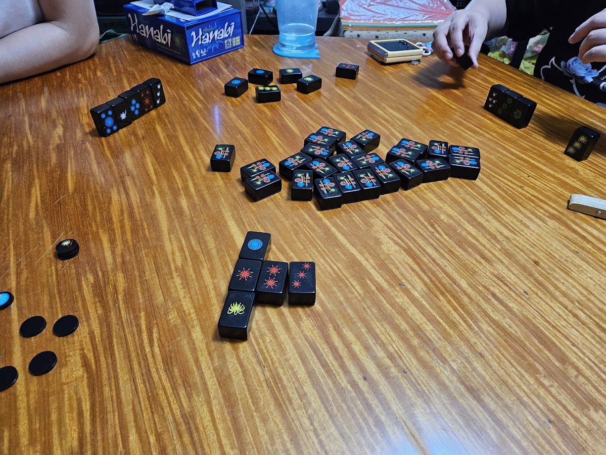Gameplay photo of the board game Hanabi Deluxe featuring various components and board state.