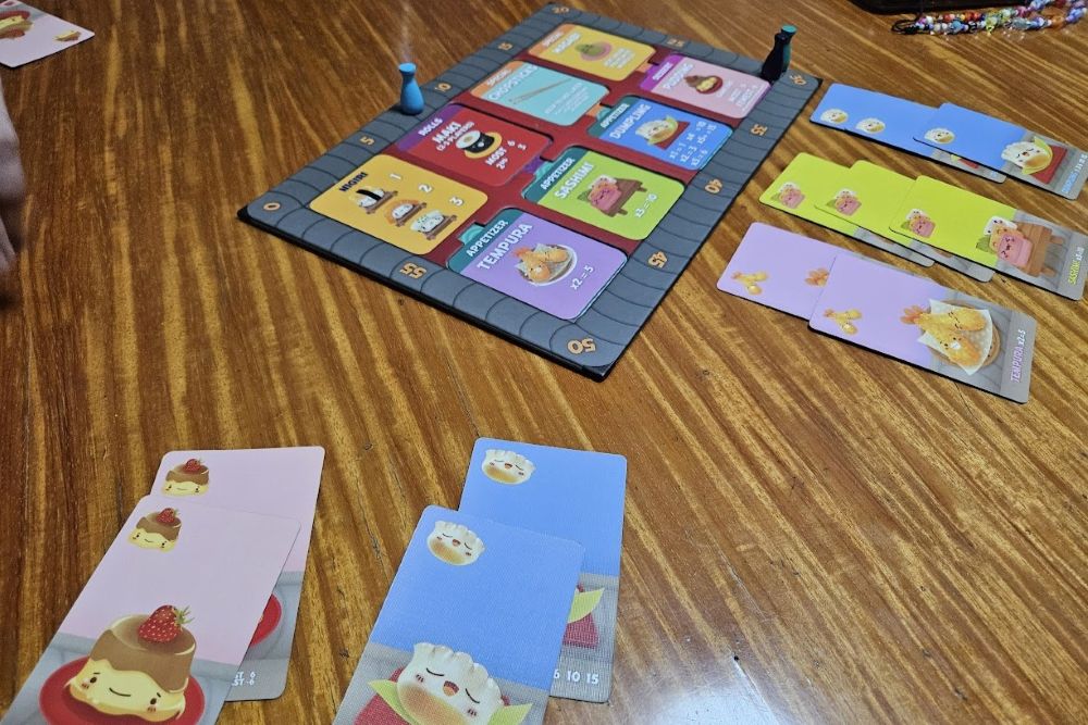 Gameplay photo of Sushi Go Party! including the conveyer belt score track.